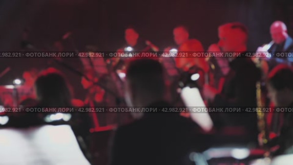 Музыканты выступают на сцене. Их силуэты освещены теплым сценическим светом. Мягкий фокус и рассеянный свет создают мечтательную, динамичную атмосферу классического концерта. Размытое видео. Стоковое видео, видеограф Воловодов Владимир / Фотобанк Лори