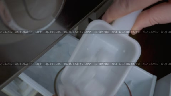 Набор льда лопаткой в стакан. Крупным планом показан процесс, как человек аккуратно набирает лёд лопаткой и заполняет им прозрачный стакан. Идеально для иллюстрации приготовления напитков, кулинарии или работы в баре. Стоковое видео, видеограф Анна Чижова / Фотобанк Лори