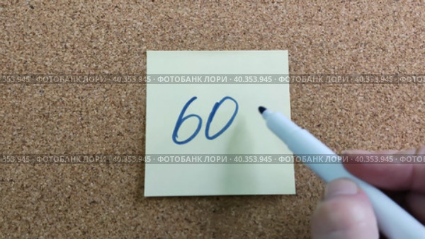 Надпись 60% на бумажном стикере приклеенном к пробковой  доске. Женщина пишет маркером на желтой бумаге. Синий фломастер в женской руке. Рукописный текст красивым почерком. Процент скидки или прибыли. The inscription is 60% on a paper sticker glued to a cork board. A woman writes with a marker on yellow paper. A blue felt-tip pen in a woman's hand. Handwritten text in a beautiful handwriting. Percentage of discount or profit. Стоковое видео, видеограф Ирина / Фотобанк Лори