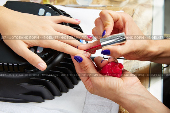 Nails painting with UV dry lamp in blue light woman hands at nail salon. Стоковое фото, агентство Ingram Publishing / Фотобанк Лори