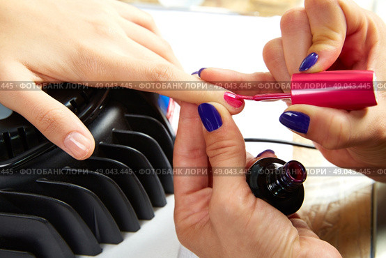 Nails painting with UV dry lamp in blue light woman hands at nail salon. Стоковое фото, агентство Ingram Publishing / Фотобанк Лори
