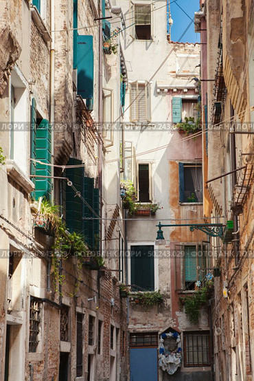 Narrow street in old town in Venice, Italy. Old buildings of mediveval times with ancient architecture.. Venetian buildings in Italy. Стоковое фото, агентство Ingram Publishing / Фотобанк Лори