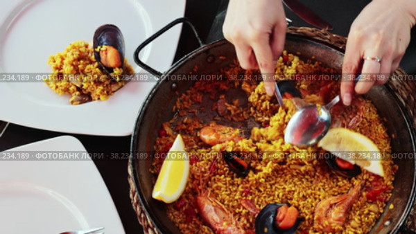 National Spanish dish is paella with seafood, cooked in a pan of rice with saffron, with the addition of the gifts of the sea. Decorated with a slice of lemon. Стоковое видео, видеограф Яков Филимонов / Фотобанк Лори