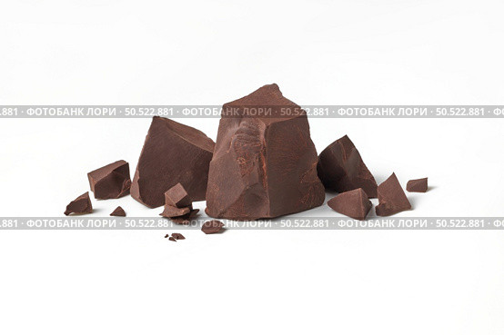 Natural dark chocolate pieces on white background with space for text. Perfect sweet snack.. Natural dark chocolate pieces on white background. Стоковое фото, агентство Ingram Publishing / Фотобанк Лори