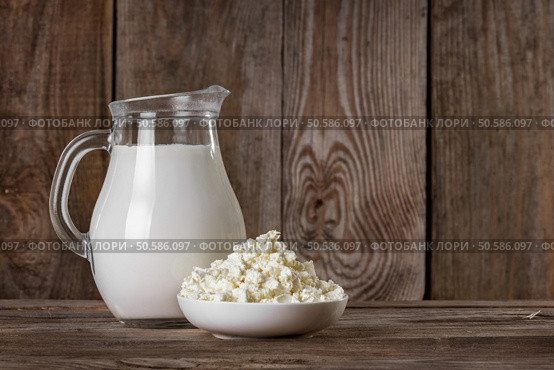 Natural rustic whole milk in a glass jug and cottage cheese on the old wooden background closeup. Natural rustic whole milk. Стоковое фото, агентство Ingram Publishing / Фотобанк Лори
