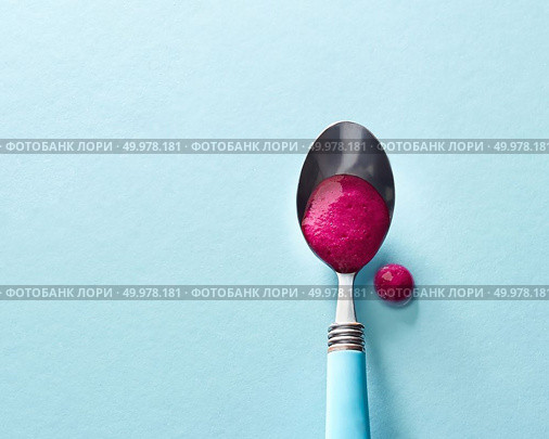 Natural smoothies of red berries in a spoon on a glass blue background and cocktail drop on the surface with soft shadows. Top view. Top view of smoothies of red berries in a spoon on a glass blue background. Стоковое фото, агентство Ingram Publishing / Фотобанк Лори
