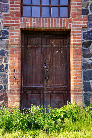 Neglect single wooden door in old city house. Old cast house wall with wooden door and window. Стоковое фото, агентство Ingram Publishing / Фотобанк Лори