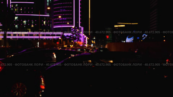 Nighttime car traffic in a major city. Beautiful backlighting of the city from a hotel. Light defocus. Night city life. Стоковое видео, видеограф Воловодов Владимир / Фотобанк Лори