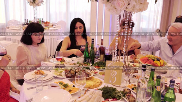 Nizhny Novgorod, Russia, Kazanskoye shosse 29, 08.31.2023. People at festive table with white tablecloths in restaurant eating delicious food. Нижний Новгород, Россия, Казанское шоссе, 29, 31.08.2023. Люди за праздничным столом с белыми скатертями в ресторане едят вкусную еду. Редакционное видео, видеограф Egor Sarantstv / Фотобанк Лори