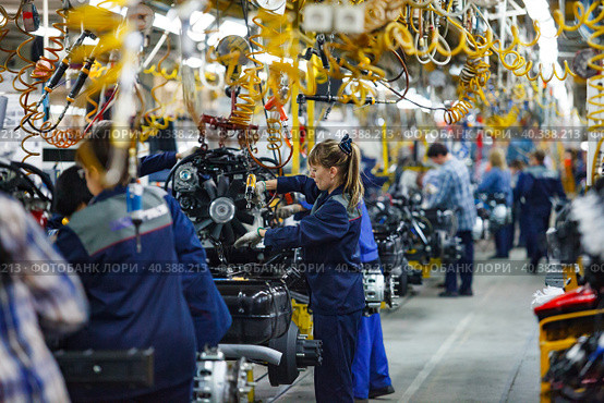 Nizhny Novgorod, Russia - November 21, 2020: GAZ car production plant. People work on assembling line. Young woman in focus only. Редакционное фото, фотограф Alexey Rezvykh / Фотобанк Лори