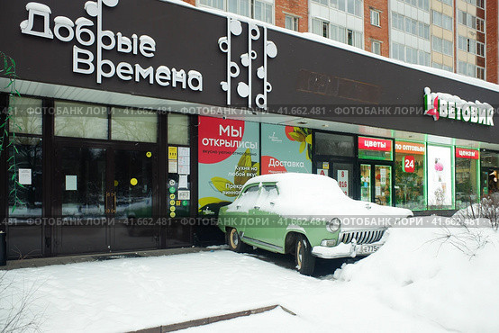 Odintsovo, Russia - January 2, 2022. Snow covered Soviet oldtimer GAZ-21 Volga in front of Dobrye Vremena (Good Times) shop in Nedelin street. Cloudy winter view. Магазин антиквариата "Добрые времена" в Одинцово. Редакционное фото, фотограф Александр Кузнецов / Фотобанк Лори