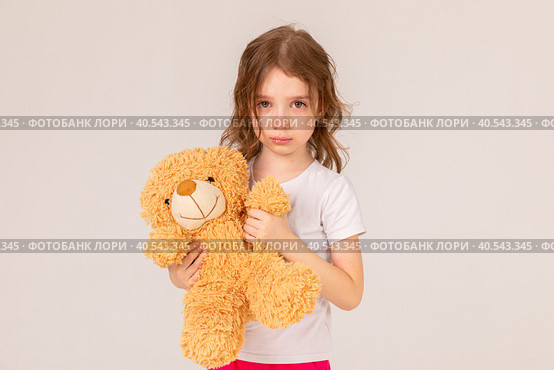 Offended little girl holding a teddy bear and crying on a white background. Стоковое фото, фотограф Ирина Михайличенко / Фотобанк Лори