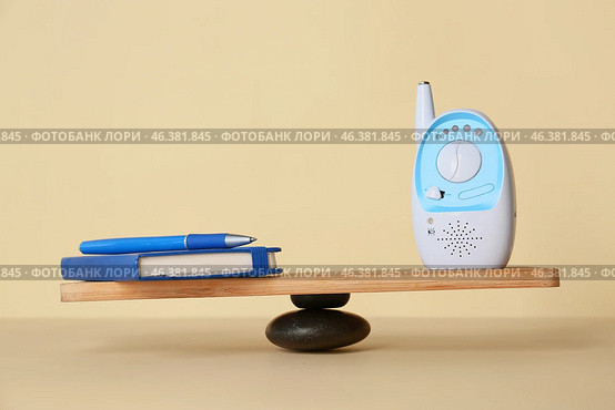 Office supplies with baby monitor on teeterboard against light background. Concept of balance. Стоковое фото, фотограф Pixel_shot / Фотобанк Лори