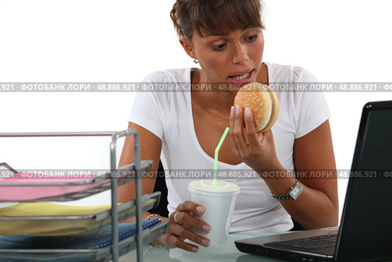 Office worker having a quick lunch in front of her computer. Стоковое фото, агентство Ingram Publishing / Фотобанк Лори
