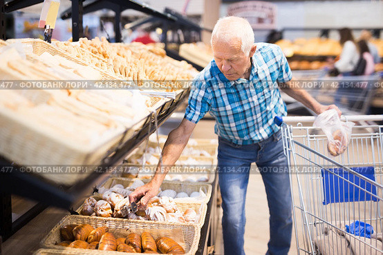 Old age senor examines bakery products in the grocery section of the supermarket. Стоковое фото, фотограф Татьяна Яцевич / Фотобанк Лори
