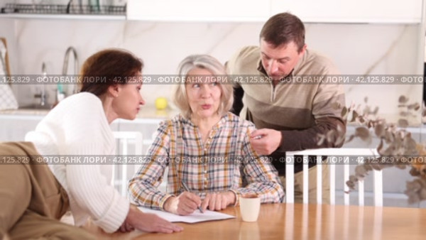 Old woman deciding and signing inheritance papers in family circle. Old woman signing papers. Стоковое видео, видеограф Яков Филимонов / Фотобанк Лори
