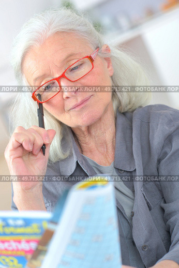 old woman playing crossword to maintain memory. Стоковое фото, агентство Ingram Publishing / Фотобанк Лори