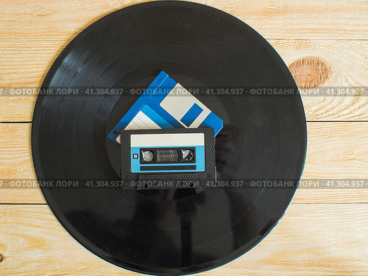 On a wooden background is a vinyl record, and on it are an audio cassette and a floppy disk. Стоковое фото, фотограф Воловодов Владимир / Фотобанк Лори