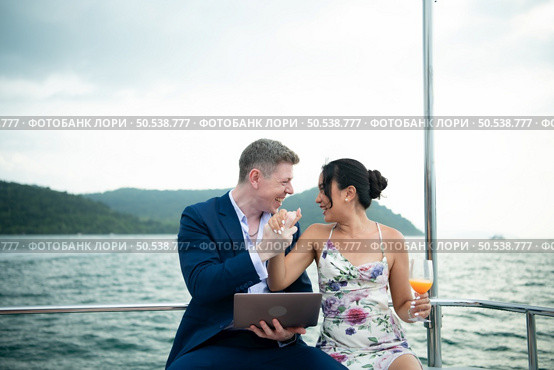 On a yacht, a businessman begins his family’s vacation. a huge project agreement was successfully closed, which was wonderful news. Стоковое фото, агентство Ingram Publishing / Фотобанк Лори