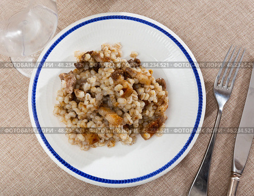 on plate,portion of stewed barley porridge with fried lard, complemented by glass of red wine and pickled cucumbers. Стоковое фото, фотограф Яков Филимонов / Фотобанк Лори