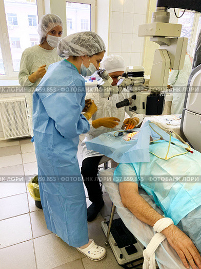 Ophthalmologist surgeon, together with assistants and nurse, performs complex operation to restore vision in a patient (2021 год). Редакционное фото, фотограф Евгений Ткачёв / Фотобанк Лори