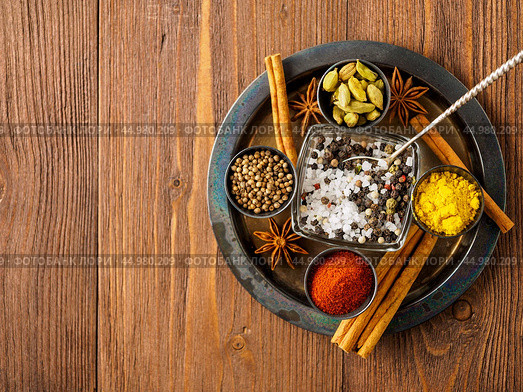 Oriental spice set - coriander, red pepper, turmeric, cinnamon, star anise, various seasonings in metall cups, on brown dark wooden table, top view, macro, empty space. Стоковое фото, фотограф Natalia Gdovskaia / Фотобанк Лори