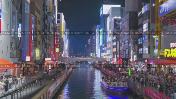 Osaka, Japan - Sep 22 2024, 4k, Panoramic view of Dotonbori river with a ship with tourists, a lot of people on embankment, there are a lot of advertising and illuminations on buildings, Osaka, Japan. Редакционное видео, видеограф Сергей Богомяко / Фотобанк Лори