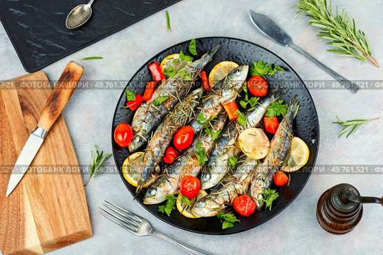 Oven baked fish sardines, with tomatoes, lemon and rosemary. Top view.. Whole roasted fish with lemon slices and herbs. Стоковое фото, агентство Ingram Publishing / Фотобанк Лори