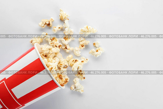 Overturned paper cup of tasty popcorn on white background. Стоковое фото, фотограф Pixel_shot / Фотобанк Лори