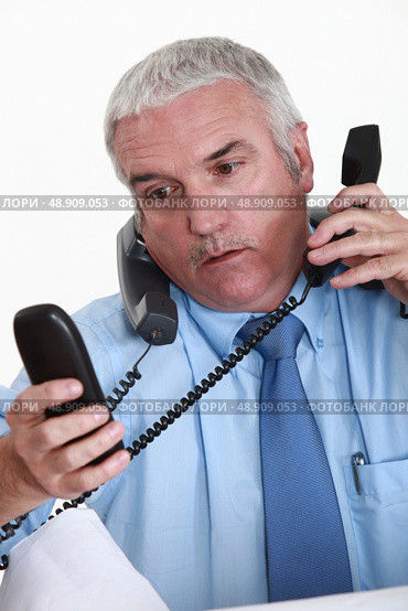 Overwhelmed white collar worker answering telephones. Стоковое фото, агентство Ingram Publishing / Фотобанк Лори