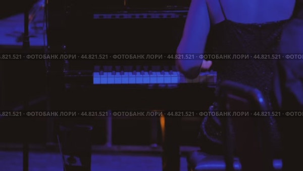 Пальцы пианиста легко скользят по клавишам рояля. Сцена залита холодным голубым светом. Женщина сидит за инструментом спиной к камере. Стоковое видео, видеограф Воловодов Владимир / Фотобанк Лори
