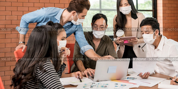 Panoramic group of asian caucasian business team meeting and brainstorm in meeting room after office reopen, they wear protective face mask as new normal practice to prevent coronavirus infection. Стоковое фото, агентство Ingram Publishing / Фотобанк Лори