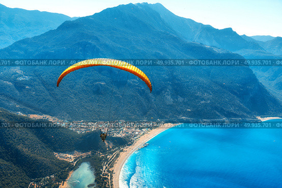 Paragliding in the sky. Paraglider tandem flying over the sea with blue water and mountains in bright sunny day. Aerial view of paraglider and Blue Lagoon in Oludeniz, Turkey. Extreme sport. Landscape. Paraglider tandem flying over the sea with blue water and mounta. Стоковое фото, агентство Ingram Publishing / Фотобанк Лори