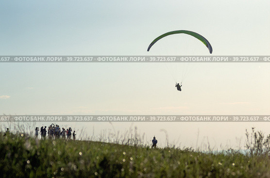 Парапланерист взлетает с вершины горы. A paraglider takes off from the top of a mountain. (2018 год). Редакционное фото, фотограф Евгений Романов / Фотобанк Лори