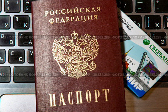 Паспорт российской федерации и единая карта Петербуржца выглядывает из него на компьютерной клавиатуре (2023 год). Редакционное фото, фотограф Татьяна Шикова / Фотобанк Лори