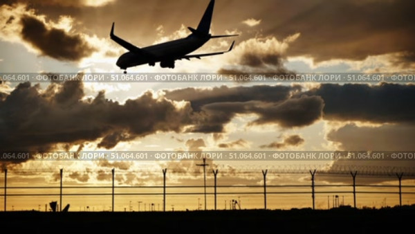Passenger airplane landing at sunset over airport fence. Стоковое видео, видеограф Mikhail Davidovich / Фотобанк Лори