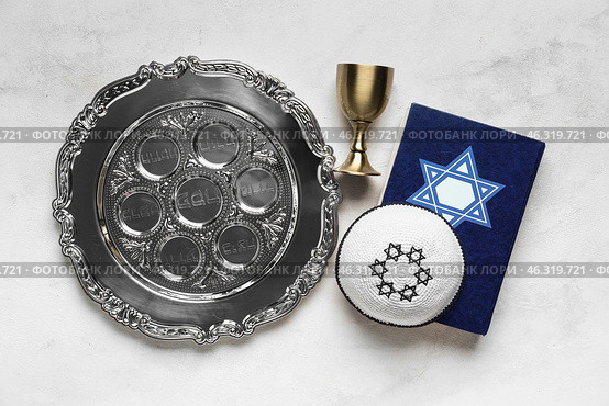 Passover Seder plate, Torah, cup and kippah on light background. Стоковое фото, фотограф Pixel_shot / Фотобанк Лори