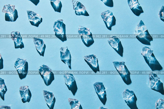 Pattern of pieces of clear glass ice on a blue background with shadows, flat lay. artificial ice cubes on a blue background with shadows. Стоковое фото, агентство Ingram Publishing / Фотобанк Лори