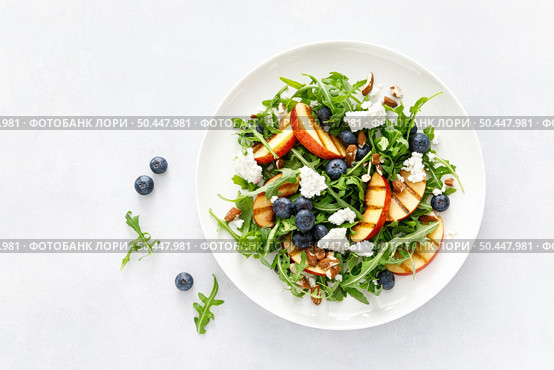 Peach, blueberry and arugula fresh fruit salad with cheese and almond nuts, top view. Стоковое фото, агентство Ingram Publishing / Фотобанк Лори