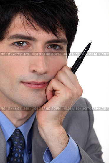Pensive man holding pen to mo face. Стоковое фото, агентство Ingram Publishing / Фотобанк Лори
