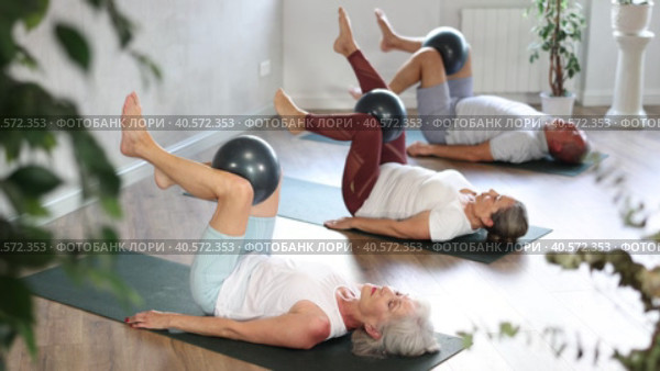 People lying on karemat, pulled bent legs to themselves and clamped soft-ball in knee. Стоковое видео, видеограф Яков Филимонов / Фотобанк Лори