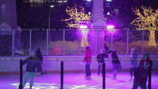 People skate in the evening on a lighted ice rink. A blizzard is raging and snow is falling. Zelenograd, Russia 28.01.2022. Редакционное видео, видеограф Юрий Поздников / Фотобанк Лори