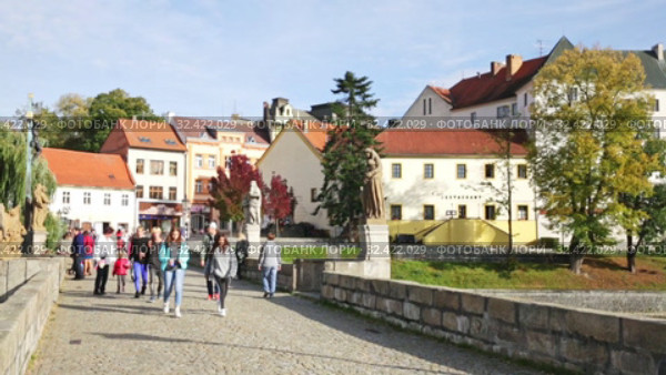 People walking along ancient Pisek Stone bridge across Otava River decorated with baroque sculptures on sunny autumn day (2019 год). Редакционное видео, видеограф Яков Филимонов / Фотобанк Лори