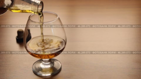 Перелейте коньяк из бутылки в бокал, стоящий на столе, закройте бутылку. Стоковое видео, видеограф Александр Собко / Фотобанк Лори