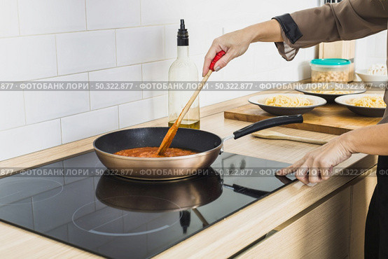 person mixing sauce pan stove. Стоковое фото, агентство Ingram Publishing / Фотобанк Лори