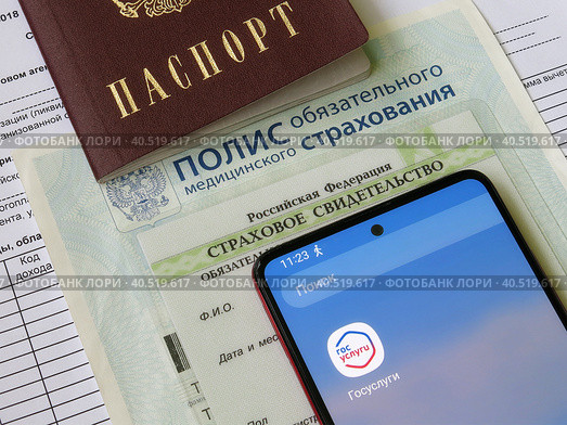 Персональные данные гражданина РФ: паспорт, медицинский полис, СНИЛС и телефон с электронным приложением Государственные слуги (2023 год). Редакционное фото, фотограф Татьяна Т / Фотобанк Лори