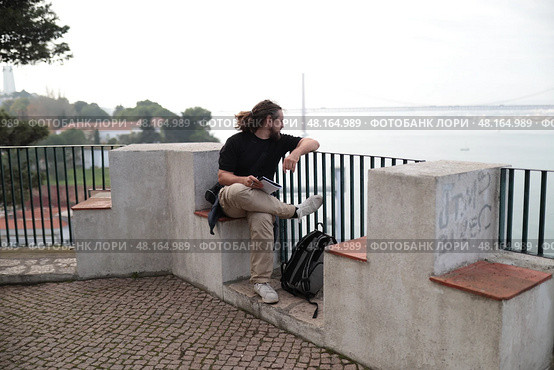 Photographer sitting and enjoying view of lisbon cityscape and tagus river. Стоковое фото, фотограф Константин Шишкин / Фотобанк Лори