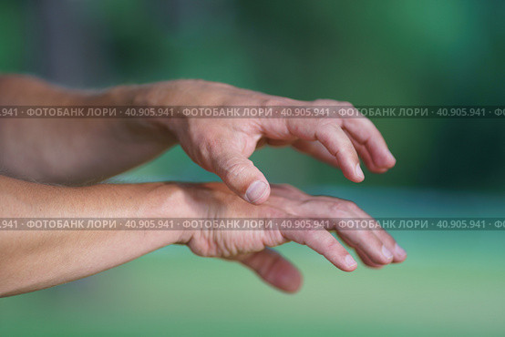 Photography of two tense female and male hands grabbing each other. They are catching or showing something . Natural green background. Close up image. Стоковое фото, фотограф YuryKara / Фотобанк Лори