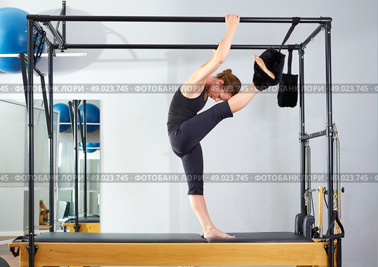 Pilates woman in cadillac split legs stretch exercise at gym. Стоковое фото, агентство Ingram Publishing / Фотобанк Лори