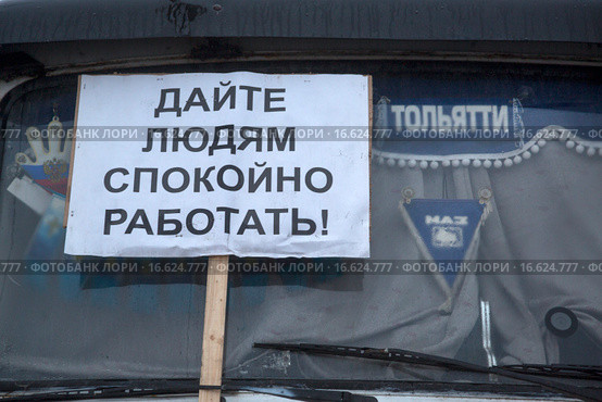 Плакат с надписью "Дайте людям спокойно работать!" на лобовом стекле грузового автомобиля на парковке дальнобойщиков в городе Химки, Россия (2015 год). Редакционное фото, фотограф Николай Винокуров / Фотобанк Лори
